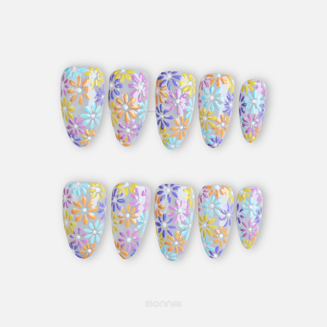Pastel Meadow press-on nails laid out with milky white base, hand-painted pastel flowers, and raised gel texture.