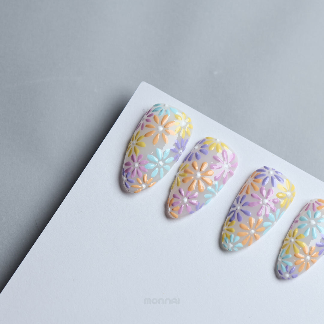 Pastel Meadow press-on nails laid out with raised pastel flower design on milky white base