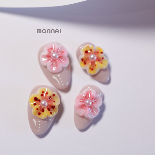 Peach Petals press-on nails with soft pink ombre, 3D flowers, pearls, and gel-gloss finish laid out in close-up