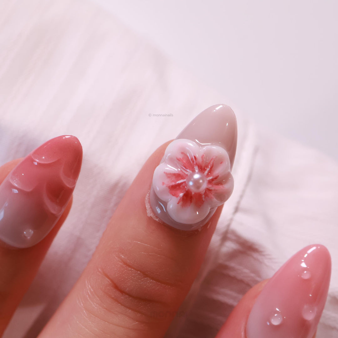 Peach Petals press-on nails in close-up, with soft pink ombre, water droplets, and a 3D flower pearl accent.