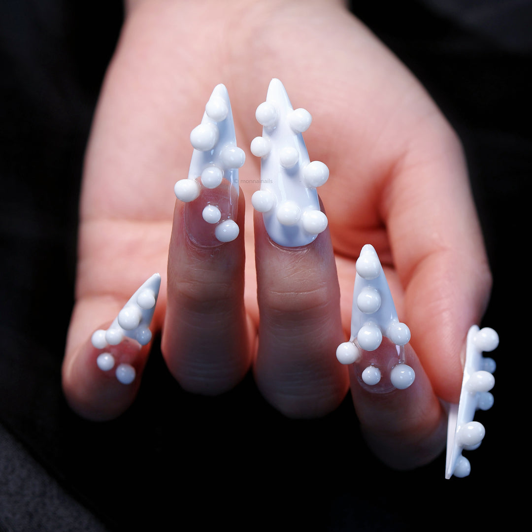 Pearl Bubbles press-on nails worn on hand, white and sheer base with 3D bubble accents.