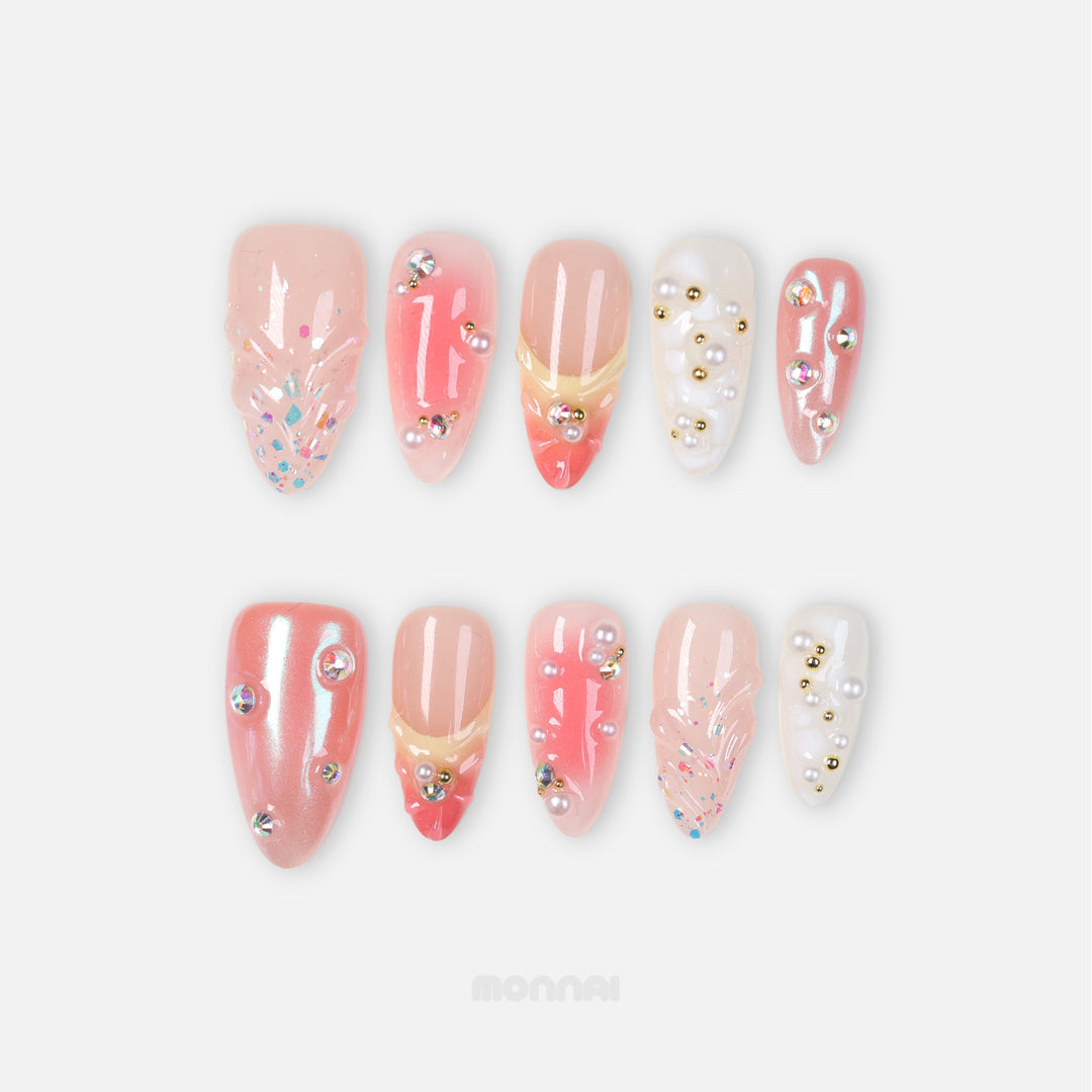 Pearl Diaries press-on nails laid out in soft nude pink, coral shimmer, milky white, pearls, and crystal accents