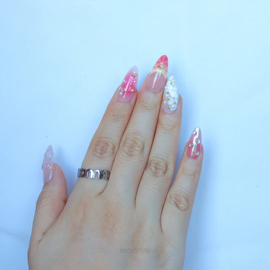 Pearl Diaries press-on nails worn on hand with sheer pink shimmer, milky white French tips, pearls, and crystal accents