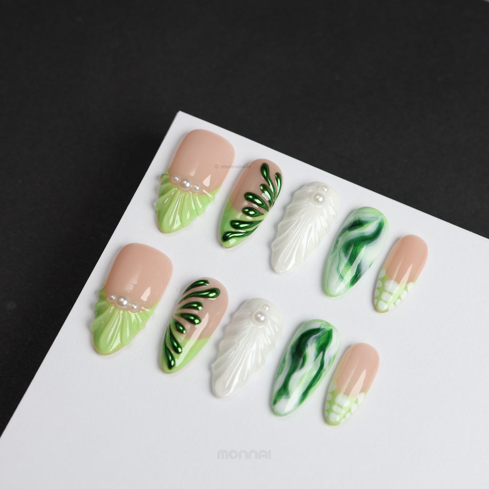 Pearl & Ivy press-on nails in nude and green leaf designs with pearl accents, laid out in a clean polished display.