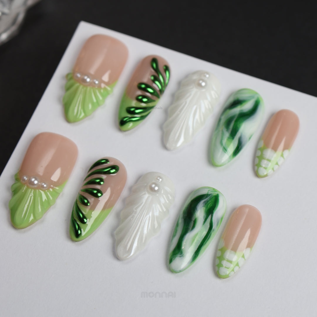 Pearl &amp; Ivy press-on nails laid out with nude, green leaf texture, glossy marbled detail, and pearl accents