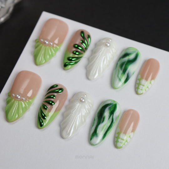 Pearl &amp; Ivy press-on nails laid out with nude, green leaf texture, glossy marbled detail, and pearl accents