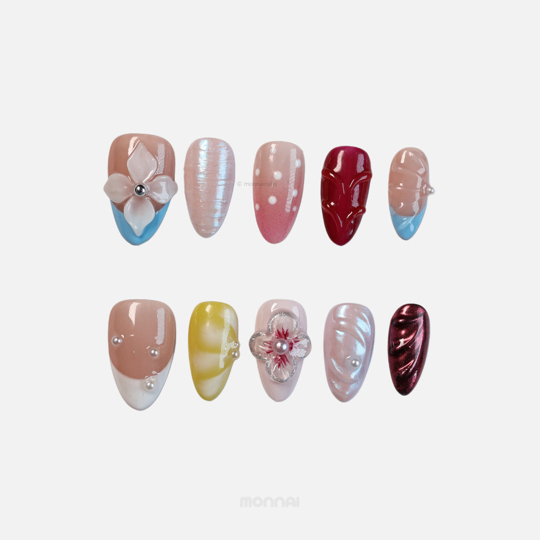 Petal Dream press-on nails laid out in eclectic mixed designs with 3D pearl flowers, chrome textures, nude, ruby and pastel colors.