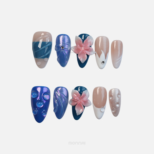Petal Waves press-on nails laid out in blue and pastel tones with pink 3D flowers, glossy details, and bubble accents