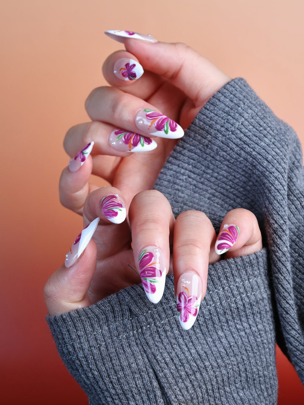 Pink Breeze press-on nails worn on hand, floral set with soft nude and milky white tones, pink flowers and green leaves