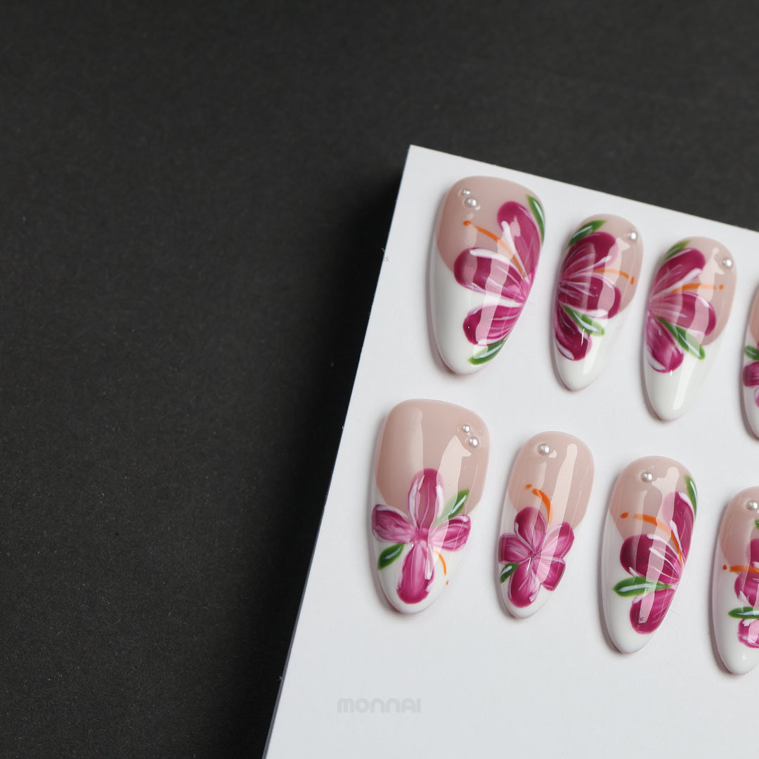 Pink Breeze floral press-on nails laid out in soft nude and milky white, with pink flowers, green leaves, and rhinestones
