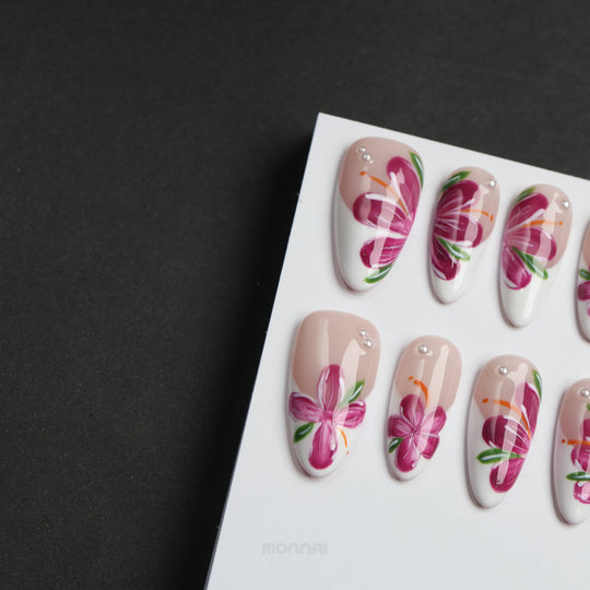 Pink Breeze floral press-on nails laid out in soft nude and milky white, with pink flowers, green leaves, and rhinestones