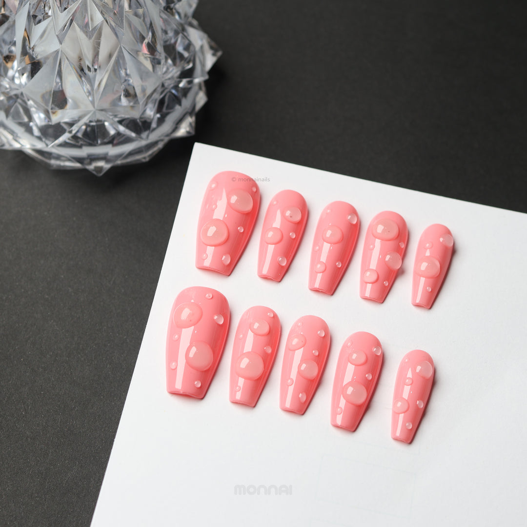 Pink Dew press-on nails with glossy pink finish and 3D dewdrop accents, laid out on a white card.