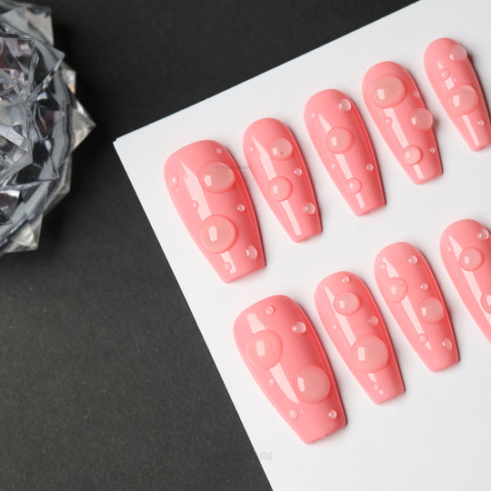 Pink Dew press-on nails in glossy pink with 3D dewdrop accents, arranged in a close-up display.