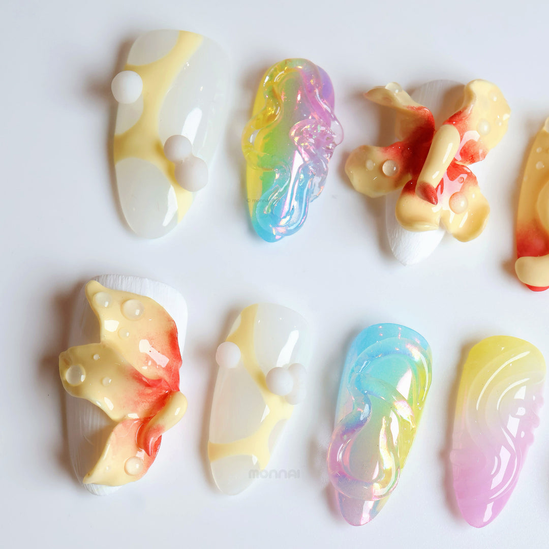 Playful Bloom press-on nails laid out in close-up, with aurora gradients, frosted white textures, and bold 3D floral accents.