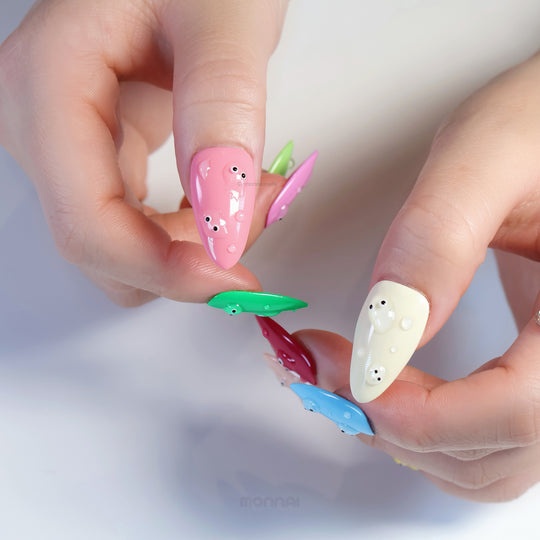 Playful press-on nails worn on hands, with glossy pastel bubbles and tiny eyes in a quirky gel-like finish.
