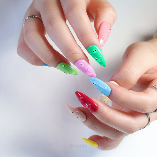 Playful press-on nails with glossy bubble-like droplets and eyes, shown worn on hands in bright pastel colors.