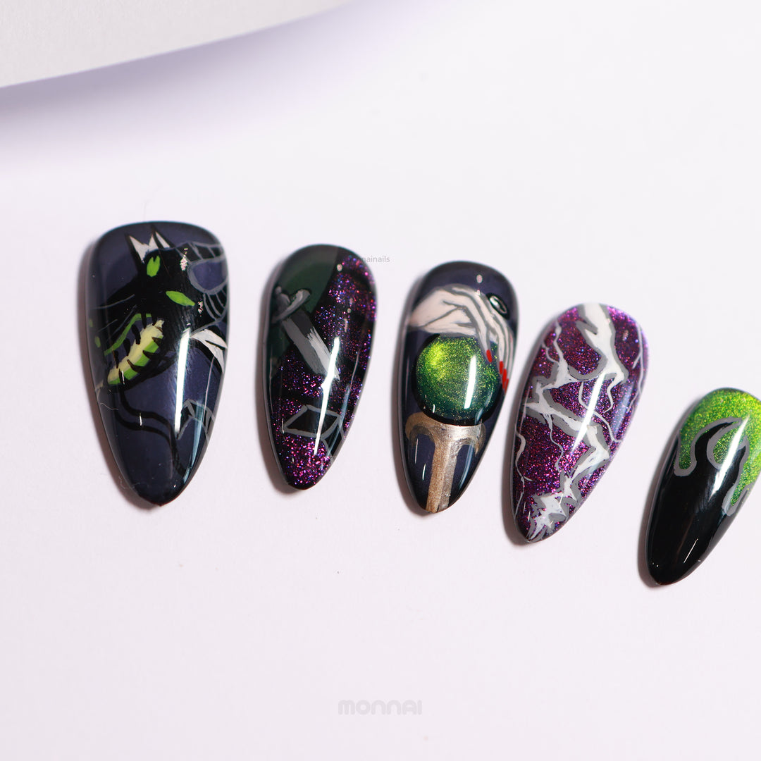 Poison Apple press-on nails laid out, with dark magic art on green and purple cat eye bases and glossy finish.