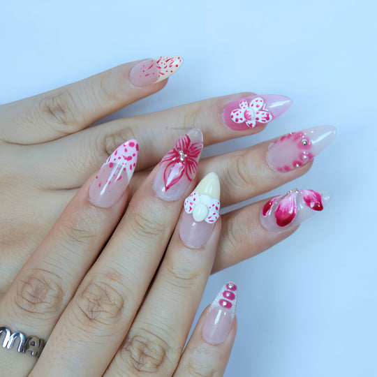 Pretty Petal Party press-on nails worn on hands with pink floral accents, rhinestones, and a pearl-centered bow