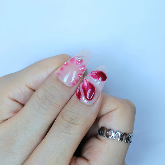 Pretty Petal Party press-on nails on hand, pink floral accents with tiny rhinestones on glossy nude bases.