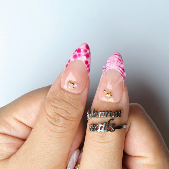 Pretty in Pink press-on nails worn on hand, pink floral accents with gold star details and glossy nude base