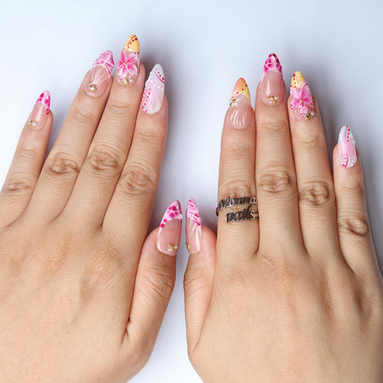 Pretty in Pink press-on nails worn on hands, with jelly nude base, pink floral motifs, 3D blooms, and gold accents.