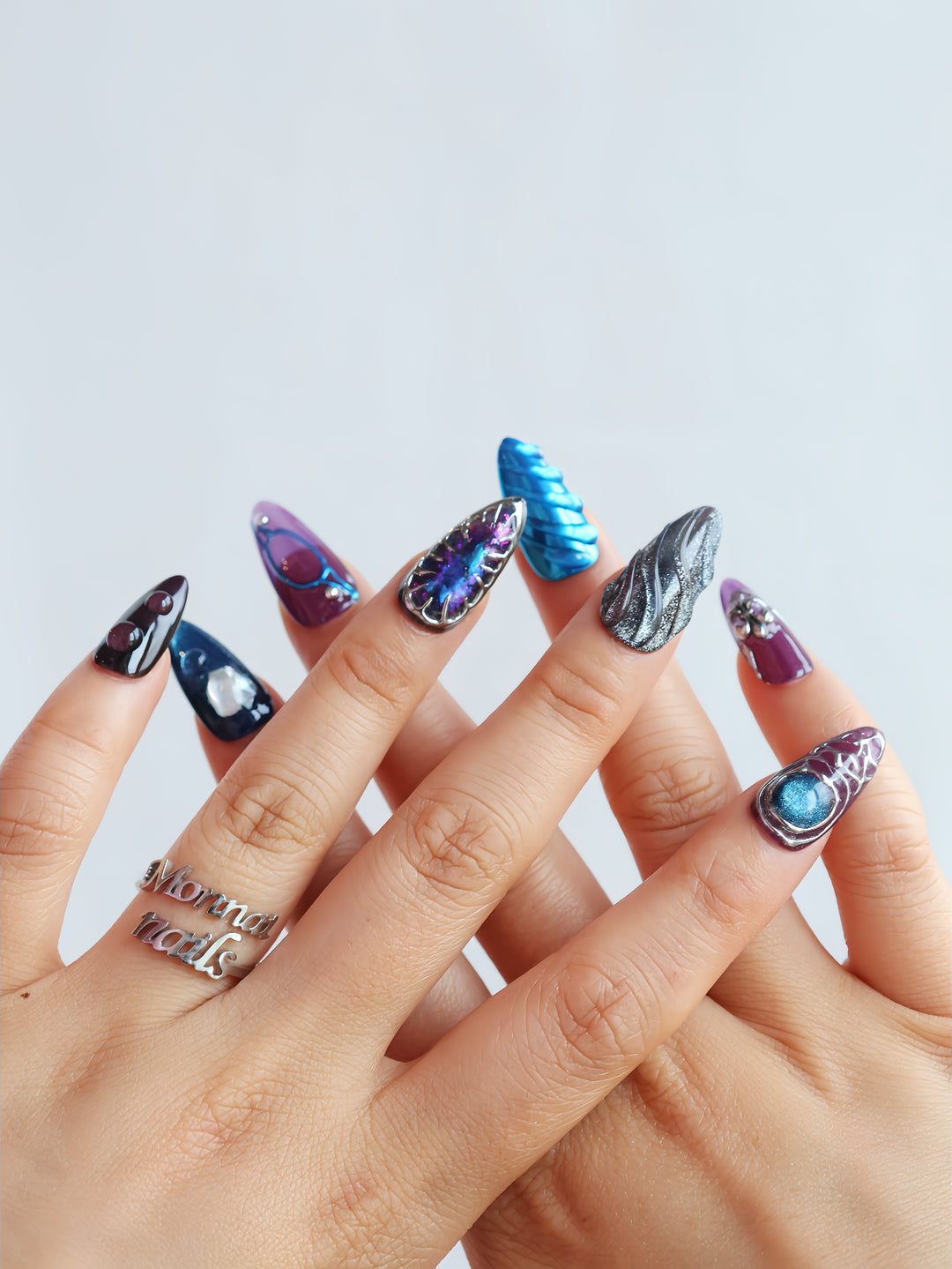 Prometheus press-on nails worn on hands, with metallic blue chrome, silver texture, and sleek futuristic shine.