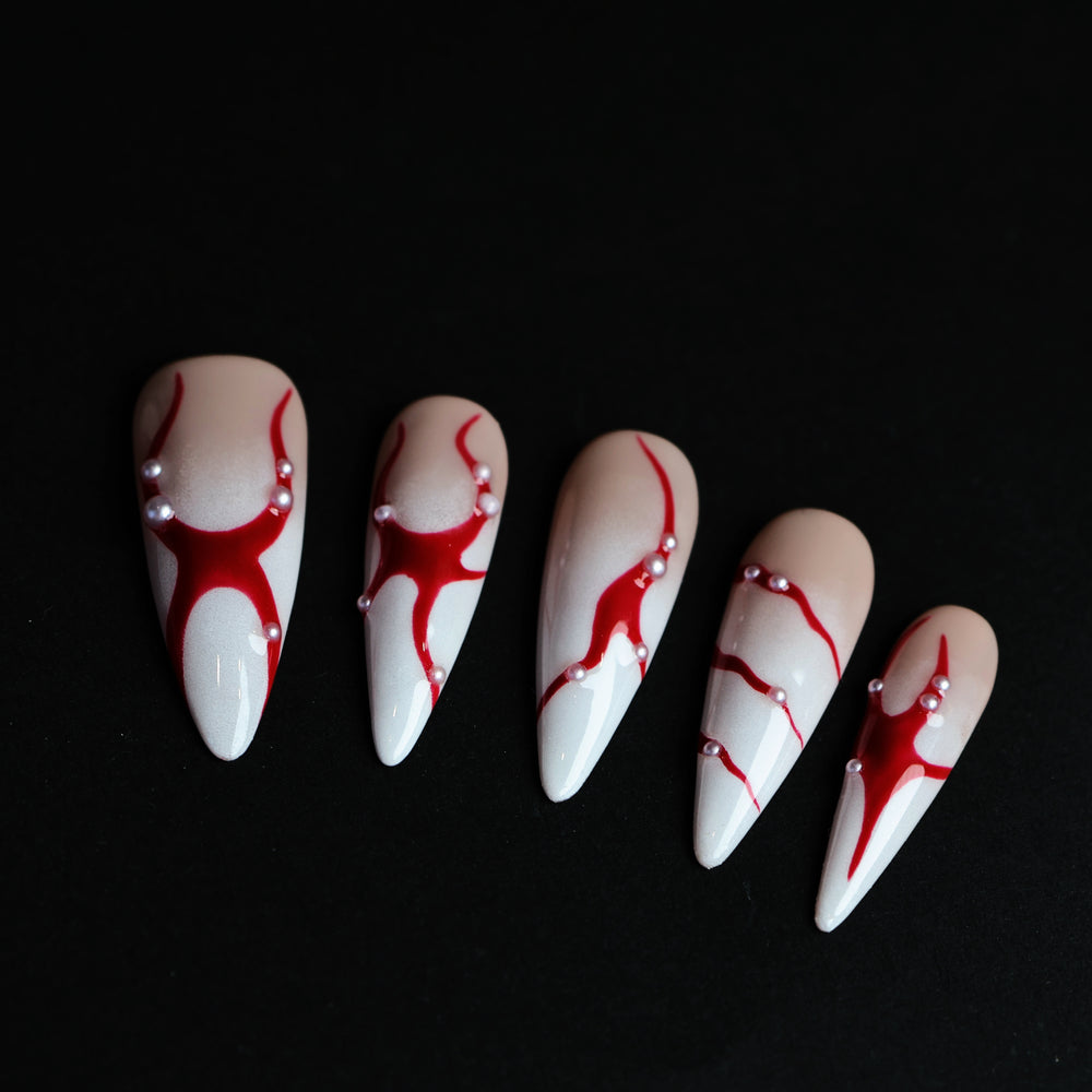R-ED press-on nails with red lines, scattered pearls, and high-gloss finish shown laid out in close-up