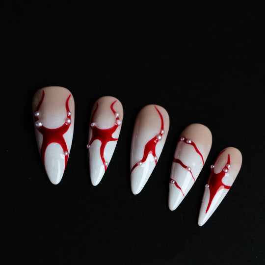 R-ED press-on nails with red lines, scattered pearls, and high-gloss finish shown laid out in close-up