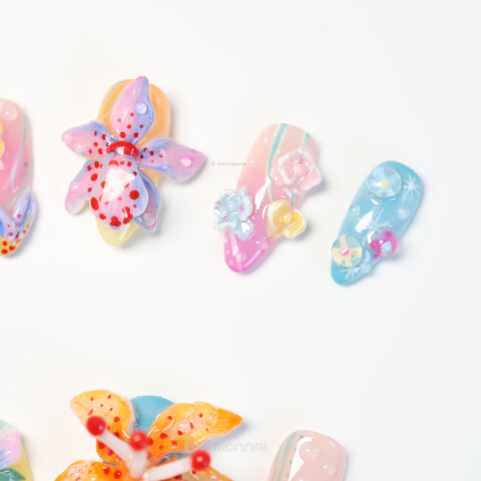 Radiant Bloom press-on nails laid out in close-up, with dreamy translucent pastel flowers and glossy sculpted details.