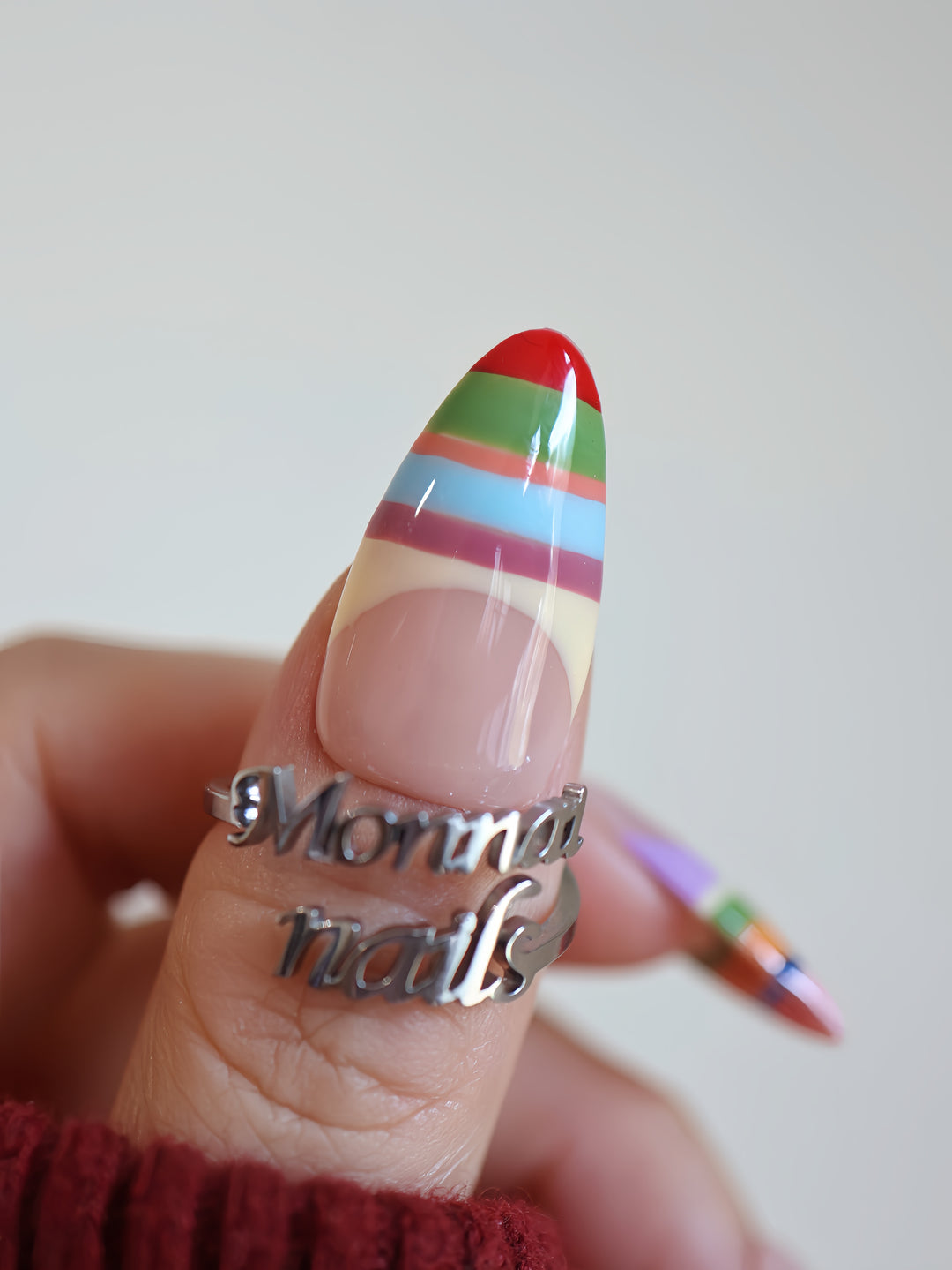 Rainbow Stripes press-on nails on hand, glossy nude base with colorful horizontal stripes and pointed shape