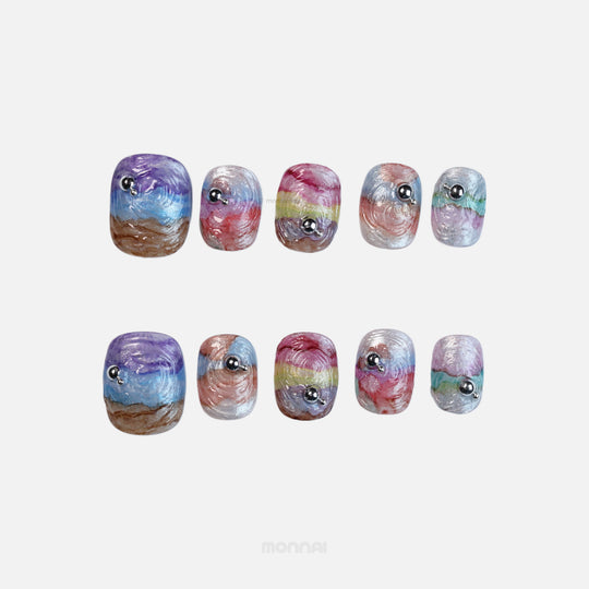 Rainbow Swirl press-on nails shown in close-up, with iridescent wavy texture and silver bead accents
