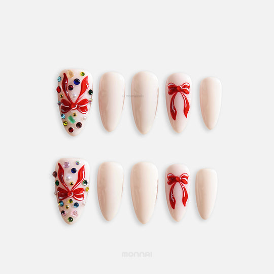 Red Bow press-on nails full set with milky white almond nails, red ribbon bows, and rhinestone accent