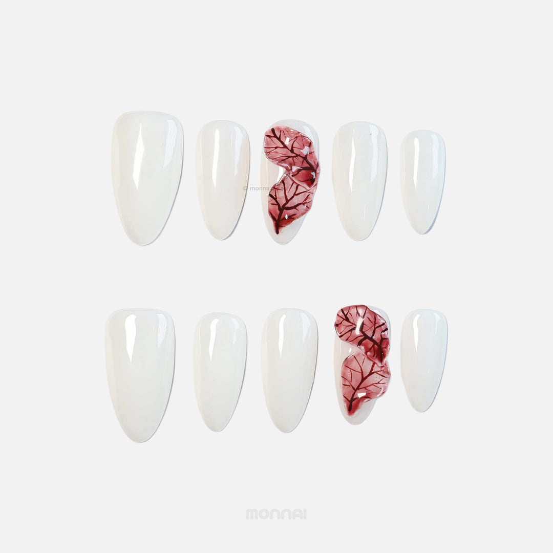 Red Leaves press-on nails laid out in milky white with sheer red leaf veining, shown in close-up.