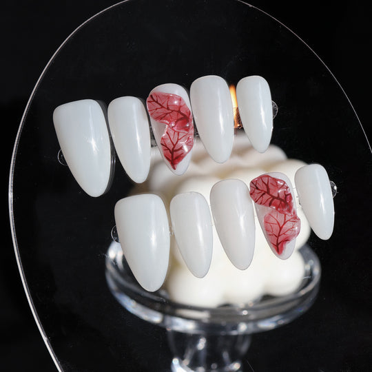 Red Leaves press-on nails on display, milky white with sheer red leaf detailing and visible veining