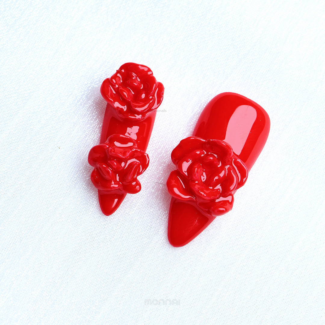 Red Rose press-on nails in glossy red with sculpted 3D rose details laid out on white fabric