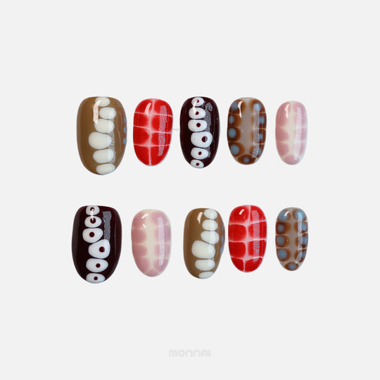 Retro Groove press-on nails laid out in close-up with retro color-blocking, abstract animal print, red, brown and soft pink.