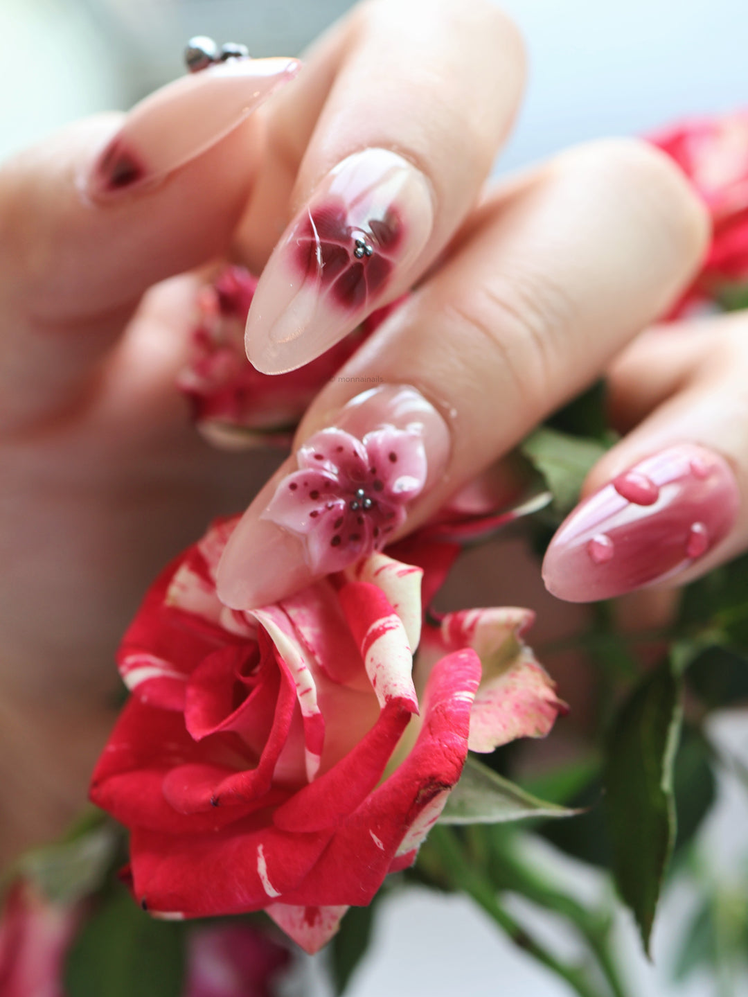 Rosé Mist press-on nails worn on hand with soft red floral accents and glossy nude finish