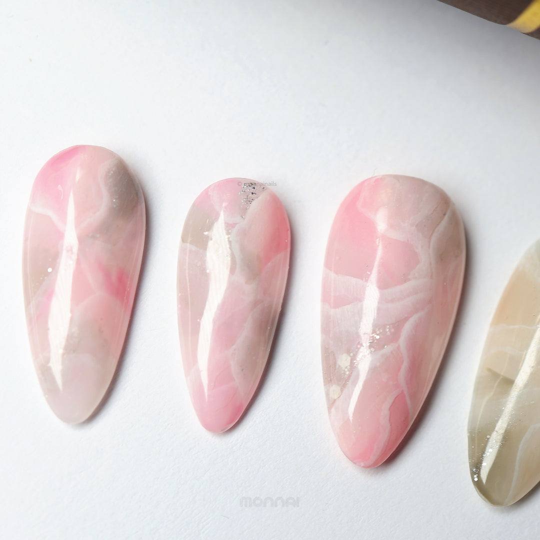 Rose Marble press-on nails laid out, showing smoky marble pink and brown tones with sheer veining and silver glitter