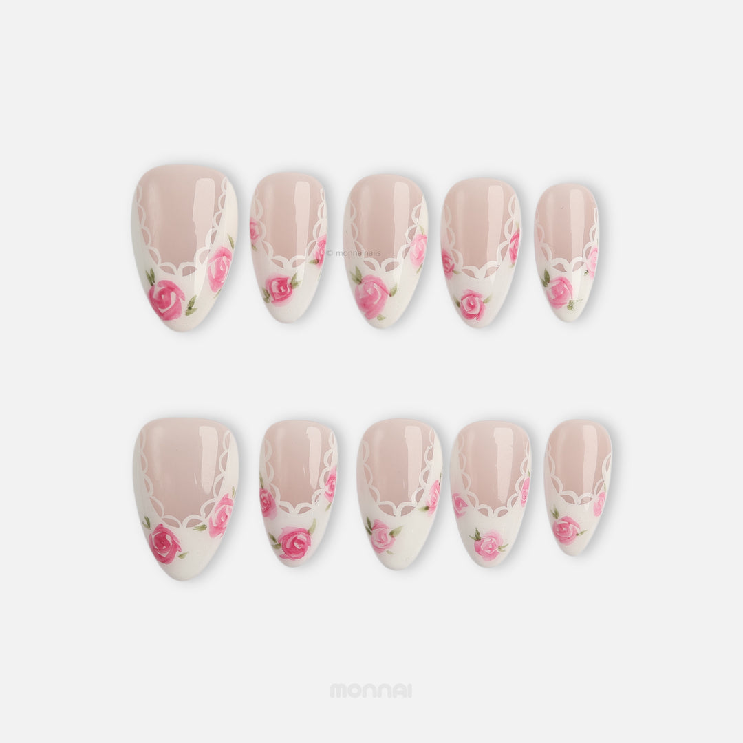 Rosy Lace press-on nails with sheer nude tones, white lace edging, and pink rose details laid out in two rows