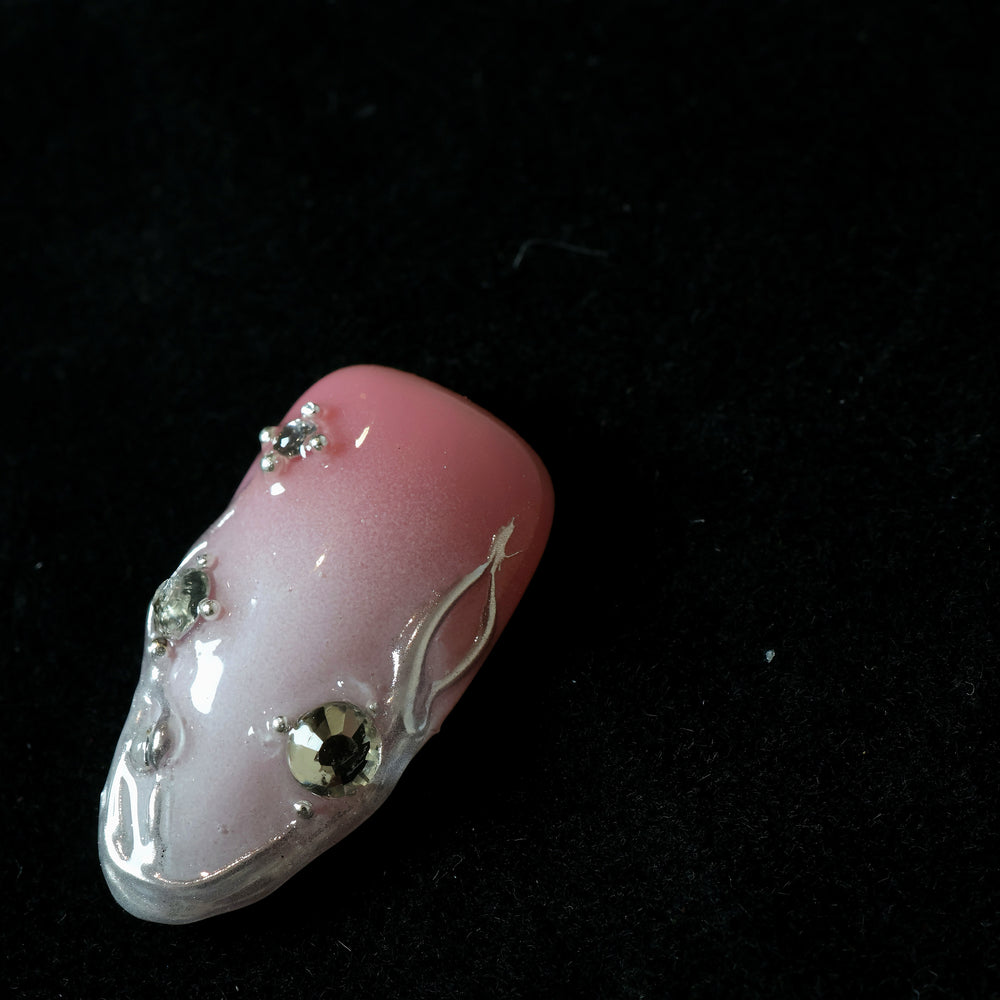 Rosy Metallic Touch press-on nails in close-up, soft pink shimmer with fluid 3D borders and clear rhinestones.