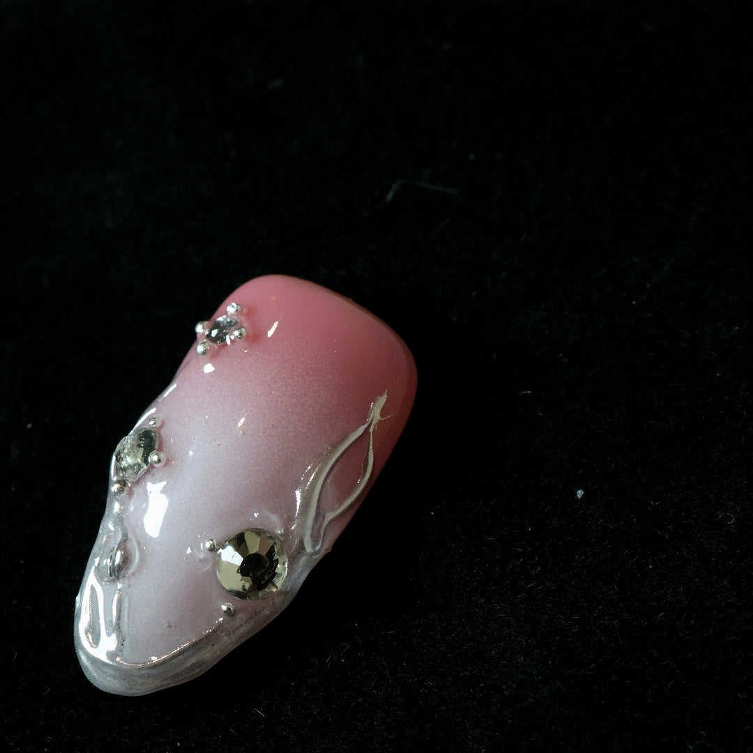 Rosy Metallic Touch press-on nails in close-up, soft pink shimmer with fluid 3D borders and clear rhinestones.
