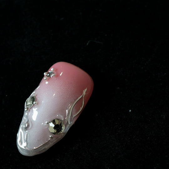 Rosy Metallic Touch press-on nails in close-up, soft pink shimmer with fluid 3D borders and clear rhinestones.