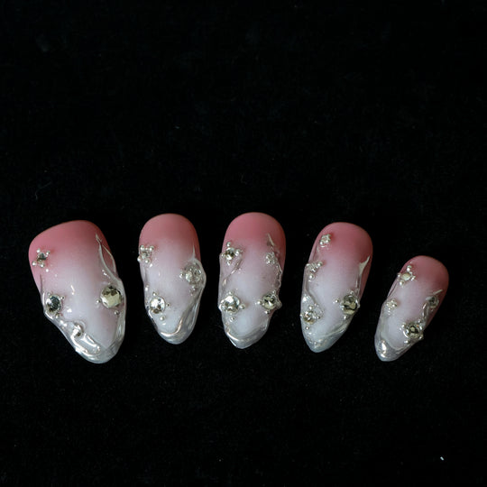Rosy Metallic Touch press-on nails laid out, showing pink shimmer gradient, fluid 3D edges, and clear rhinestones.