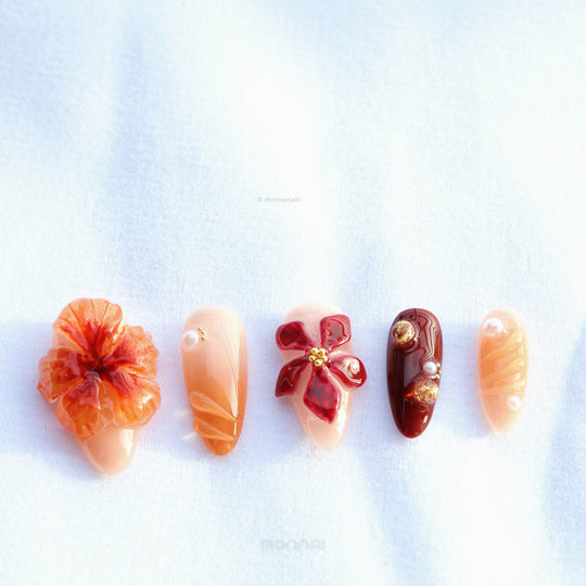 Rustic Elegance press-on nails laid out with big florals, coral and deep berry tones, gold accents, and glossy 3D details