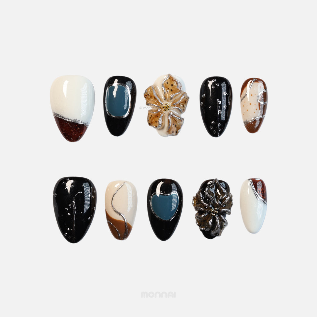 Rustic Luxe press-on nails laid out in black, white, tortoiseshell brown and muted blue with silver-edged floral accents.