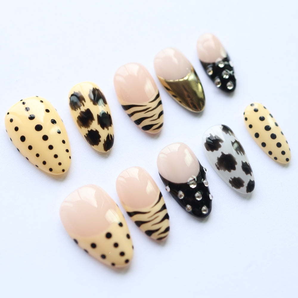 Safari Chic press-on nails laid out in a bold safari-themed mix of polka dots, zebra stripes, and gold chrome tips.