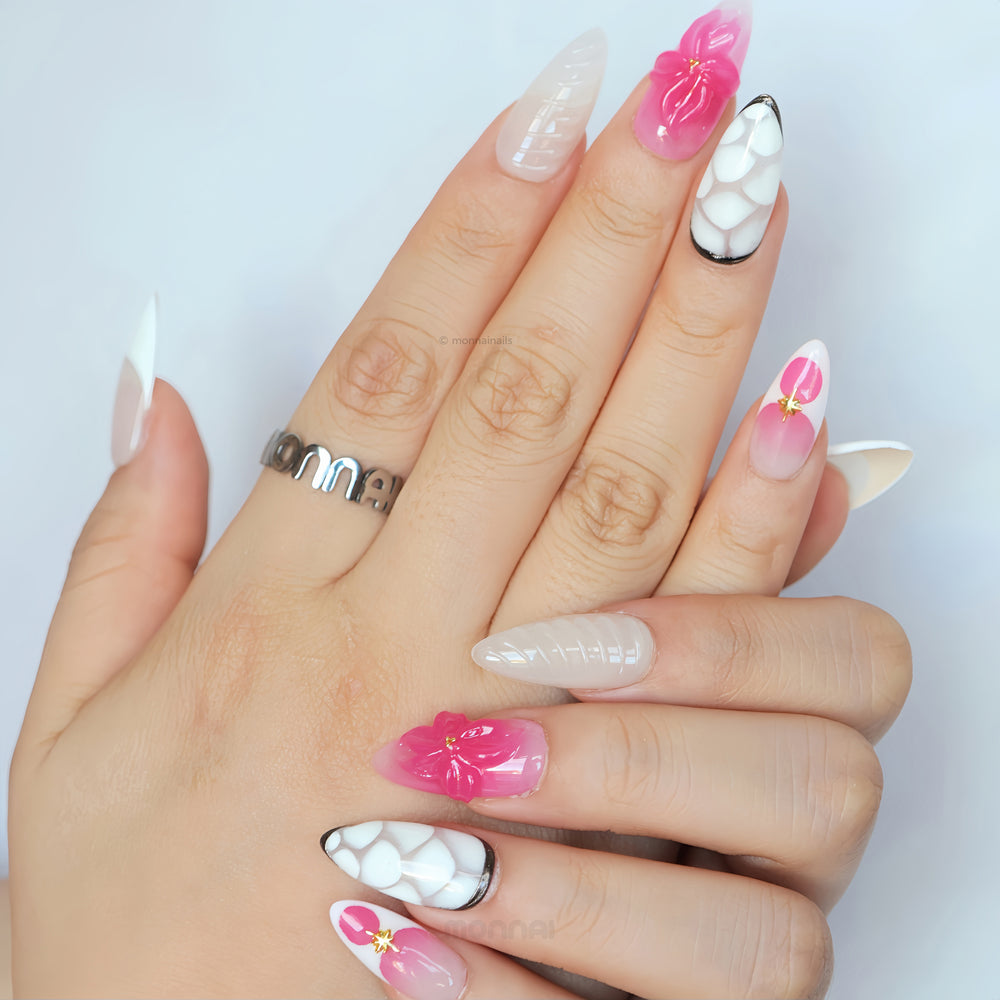 Sakura Kiss press-on nails worn on hands, with pink 3D flowers, nude French tips, and black-edged white lattice accents