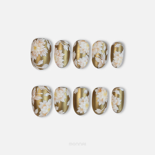 Silk &amp; Stitches gold press-on nails with white floral embroidery laid out in two rows