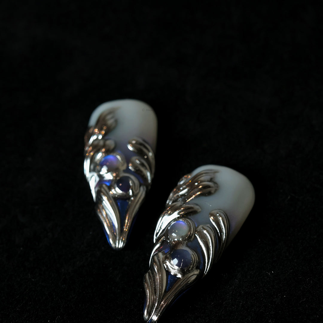 Silver Dreams press-on nails with icy white base, chrome feather-like textures, and subtle iridescent blue accents.
