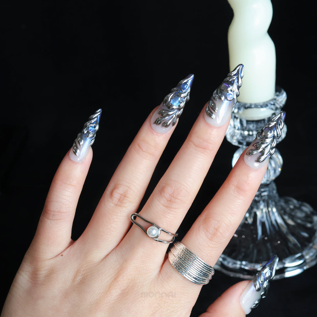 Silver Dreams press-on nails worn on hand, with icy chrome feather textures and iridescent silver accents.